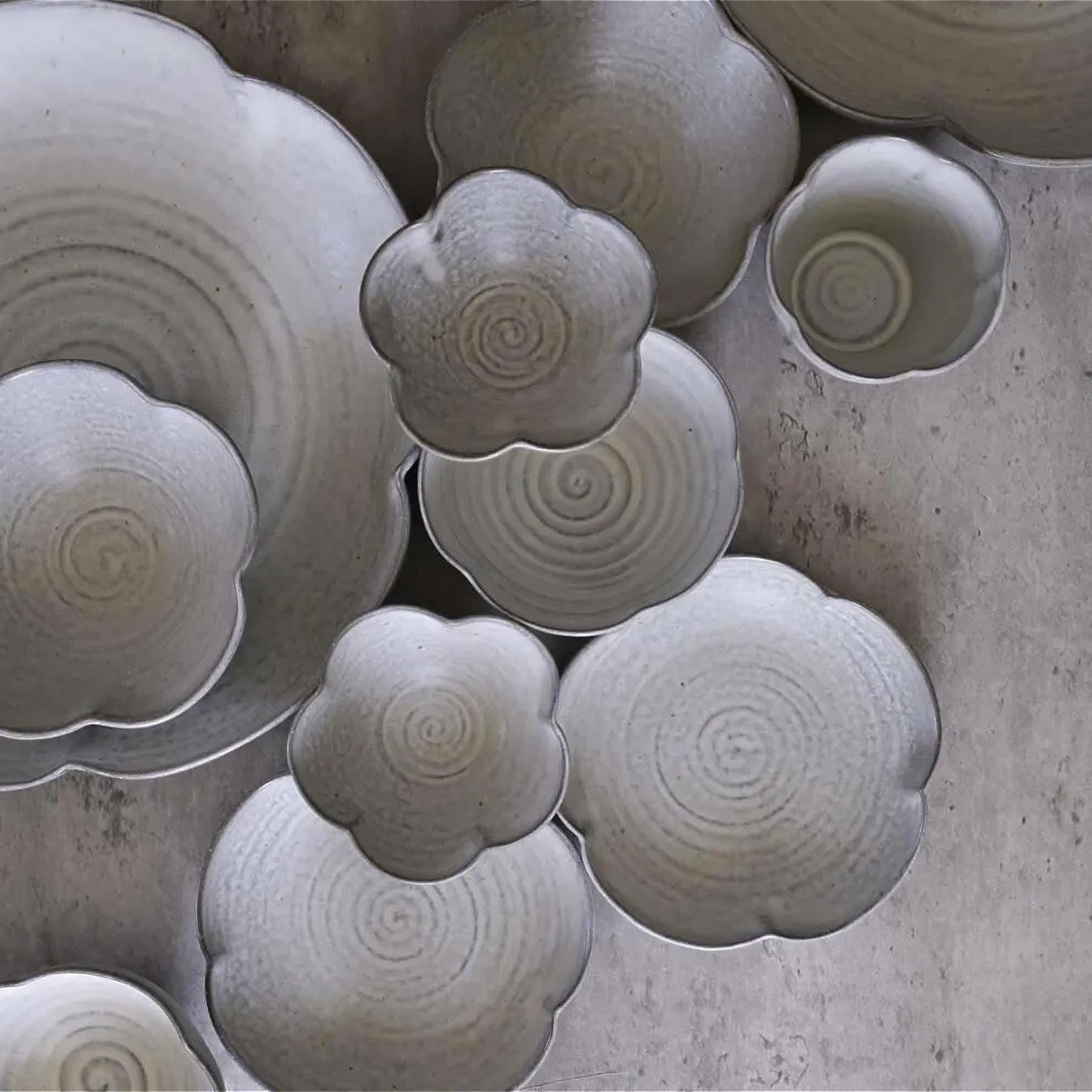Collection of ceramic bowls with textured surfaces on a concrete surface