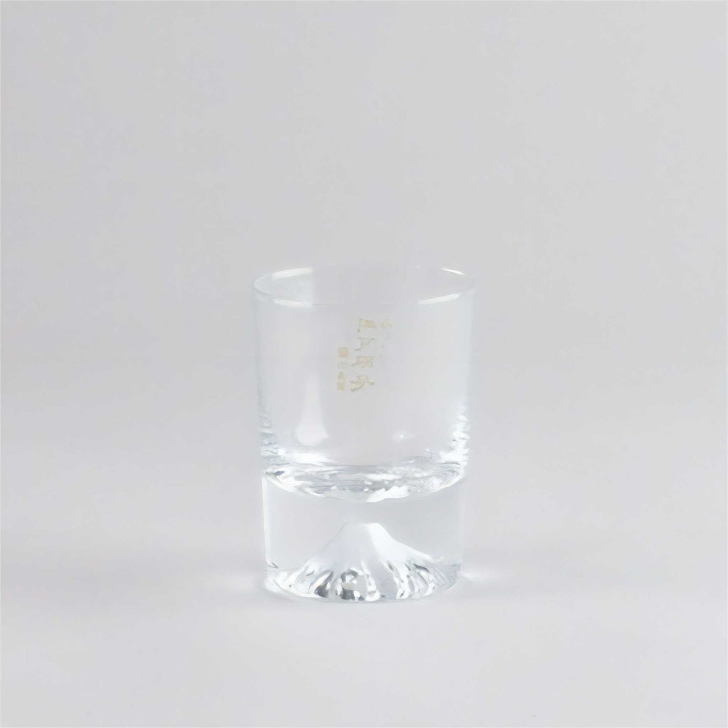 Clear glass tumbler with a gold logo on a white background