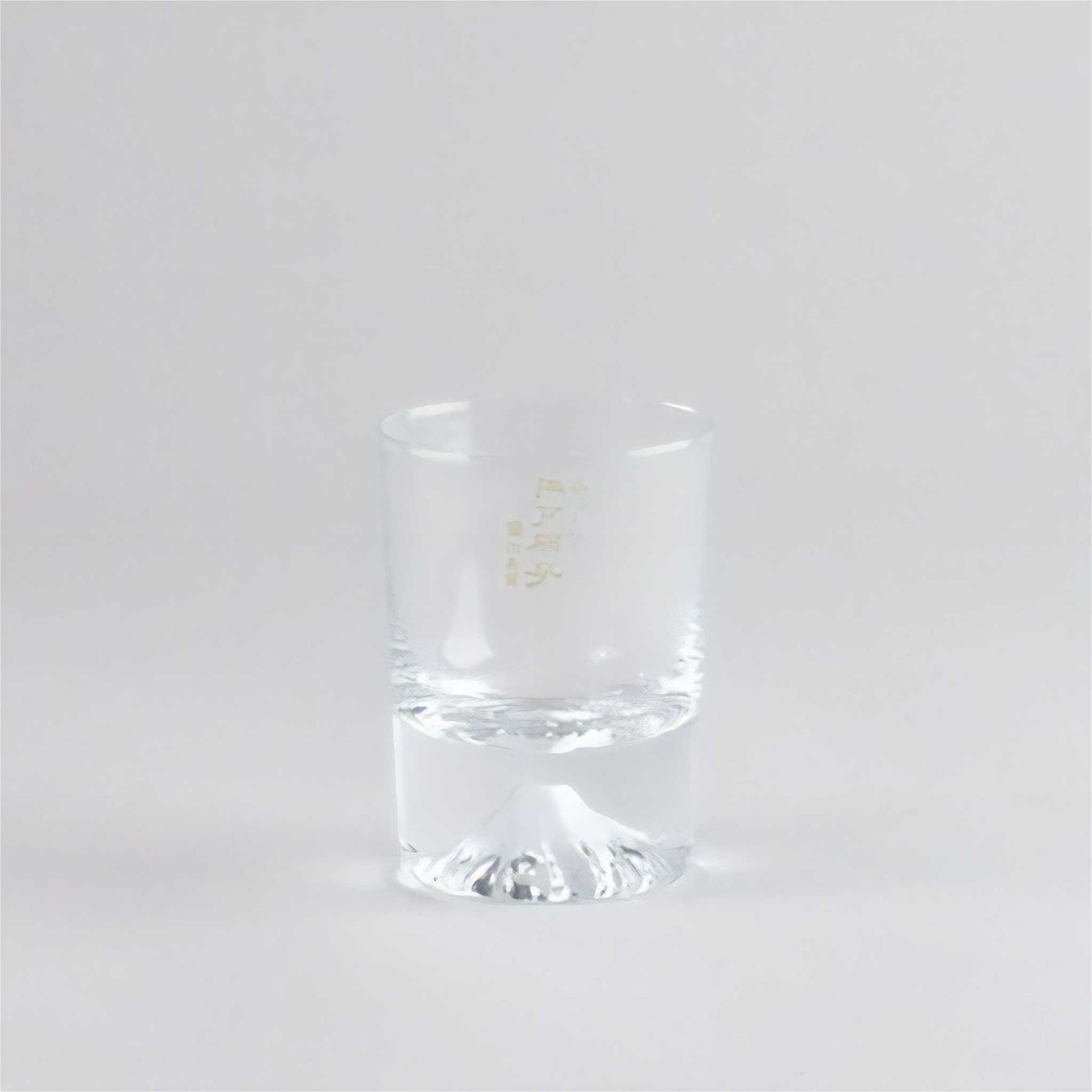 Clear glass tumbler with a gold logo on a white background