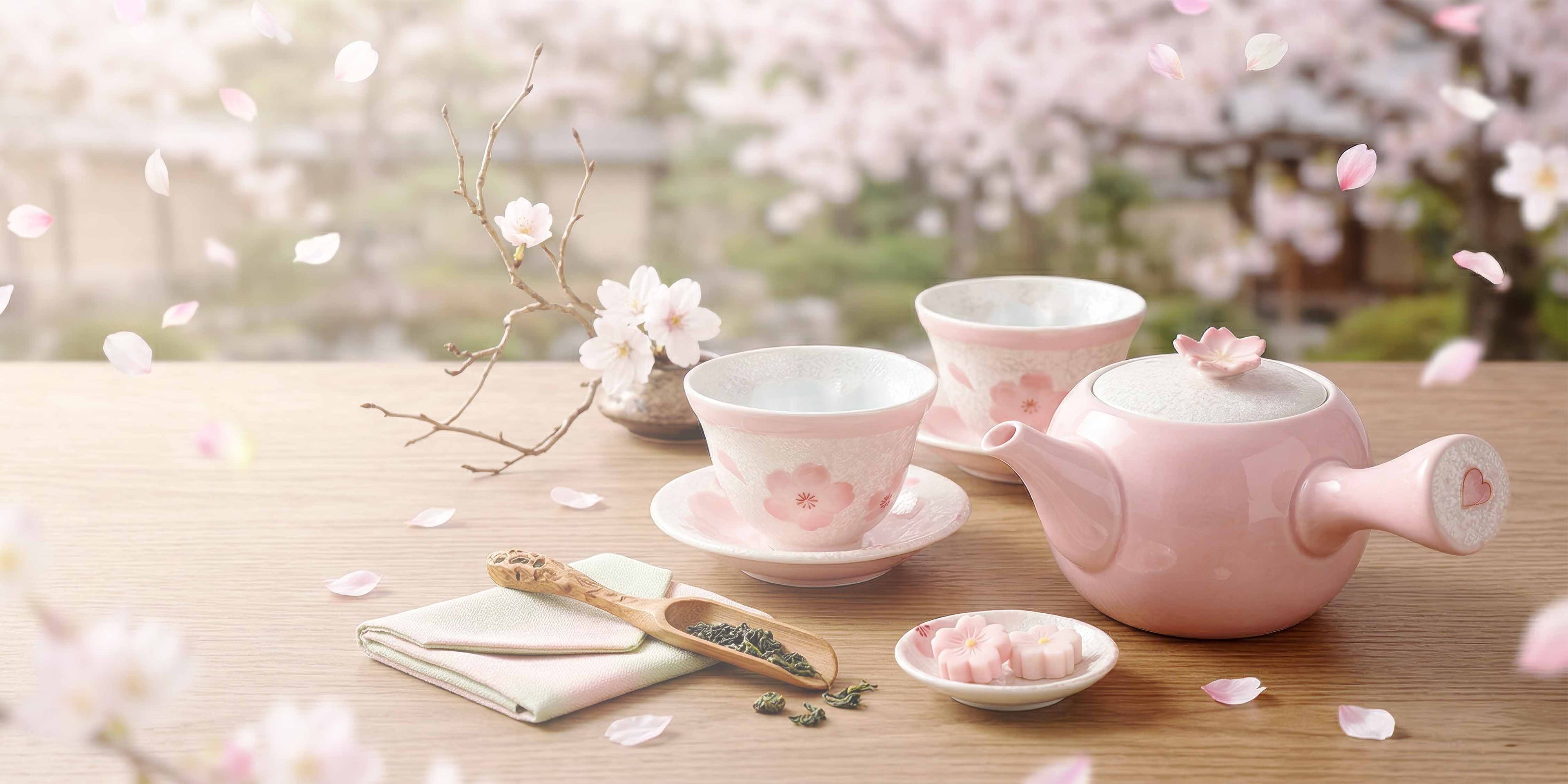 Pink ceramic tea set with cherry blossoms in the background