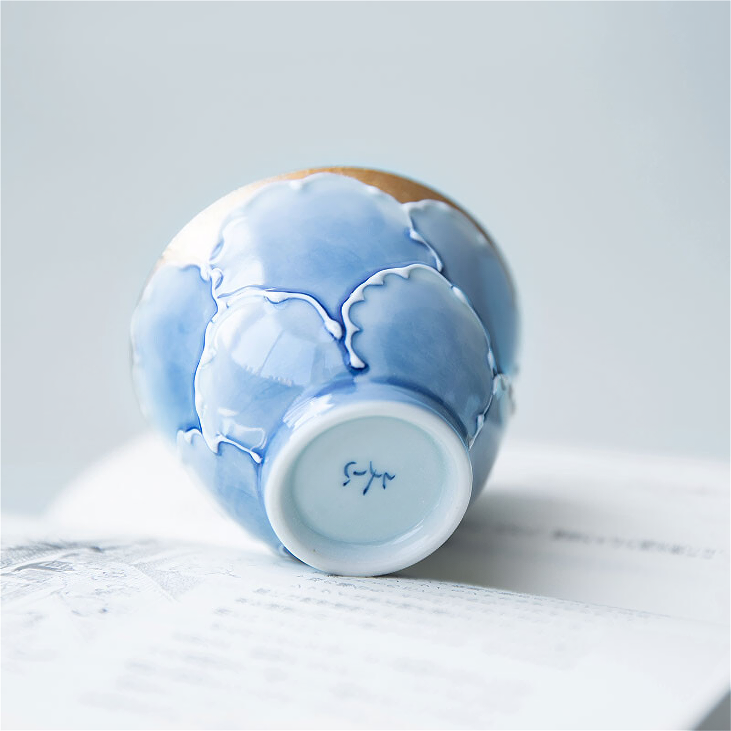 A delicate, hand-painted peony motif adorns this classic blue-and-white Arita ware tea cup, crafted from the renowned Bunzai Kiln.