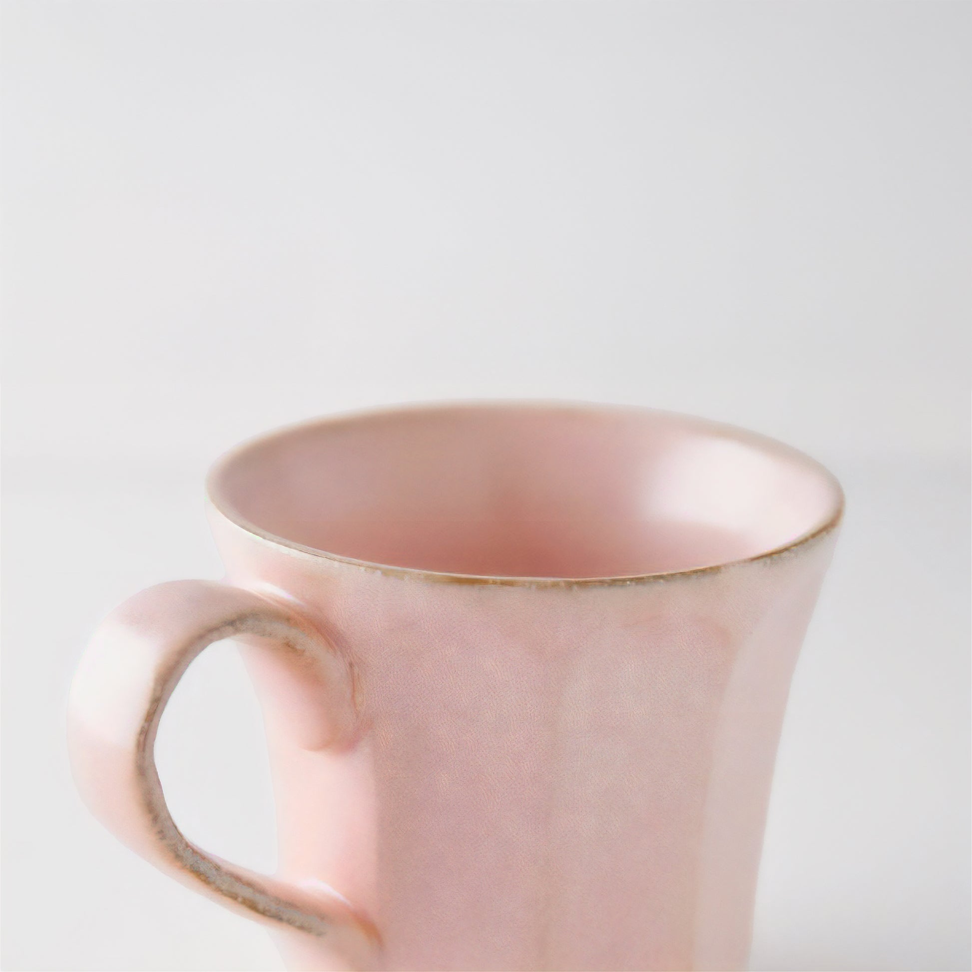 Pink mug with gold rim on a light gray background