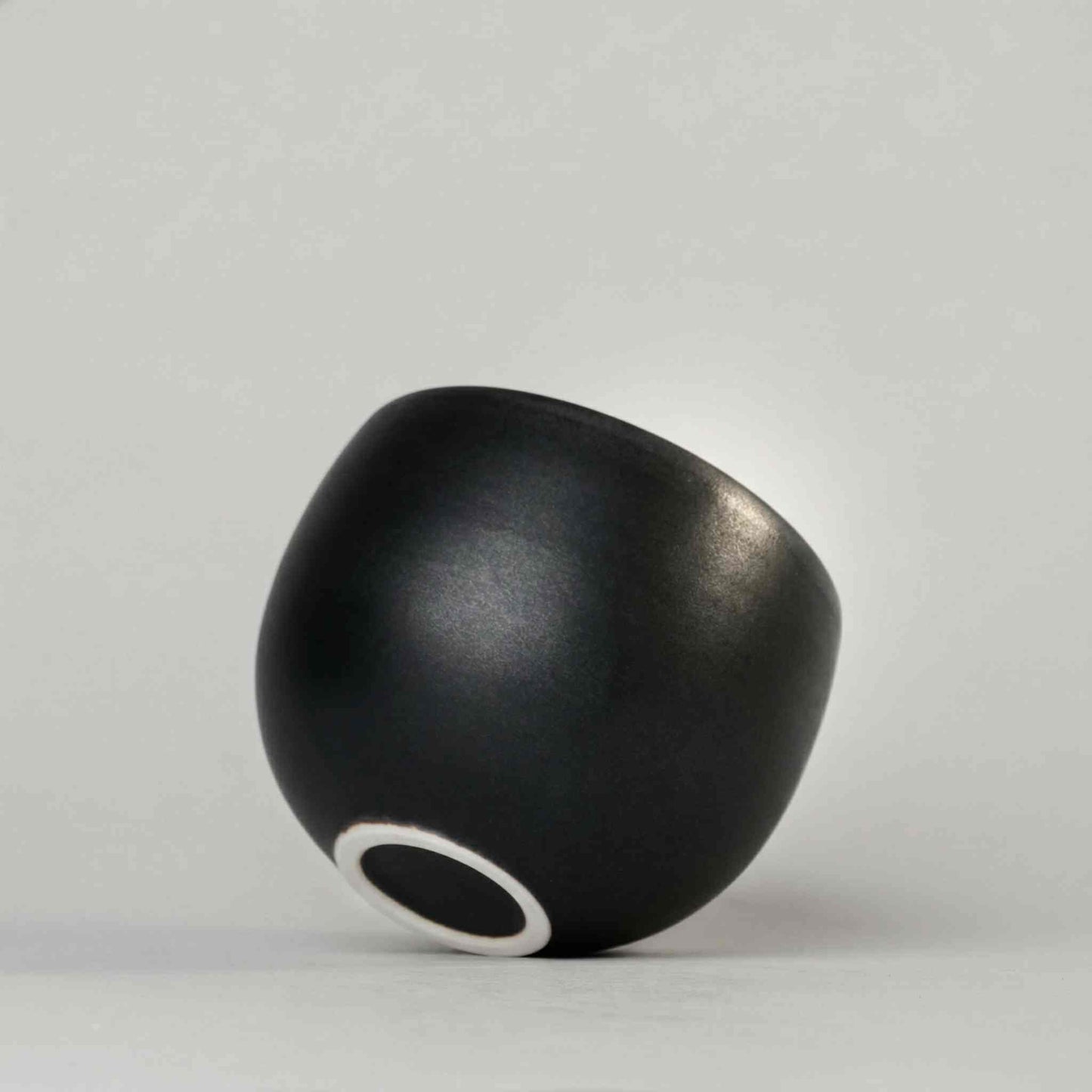 Handcrafted black and white wabi-sabi ceramic mug with saucer, Arita ware on a neutral background.