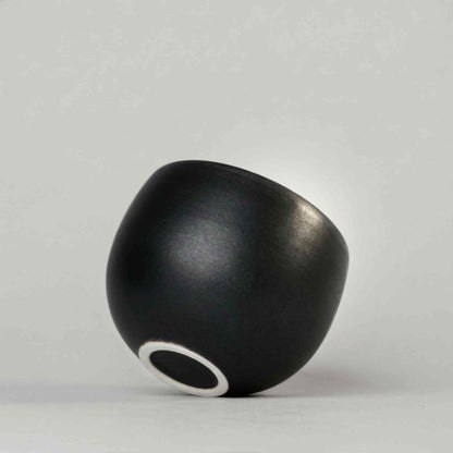 Handcrafted black and white wabi-sabi ceramic mug with saucer, Arita ware on a neutral background.
