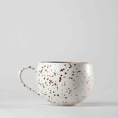 A white ceramic mug with a speckled gold and brown design, set against a plain white background.