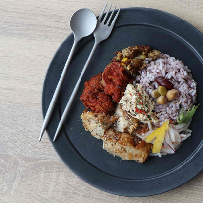 A plate of food, including rice, vegetables, and meat, served on a black plate with a fork and spoon.