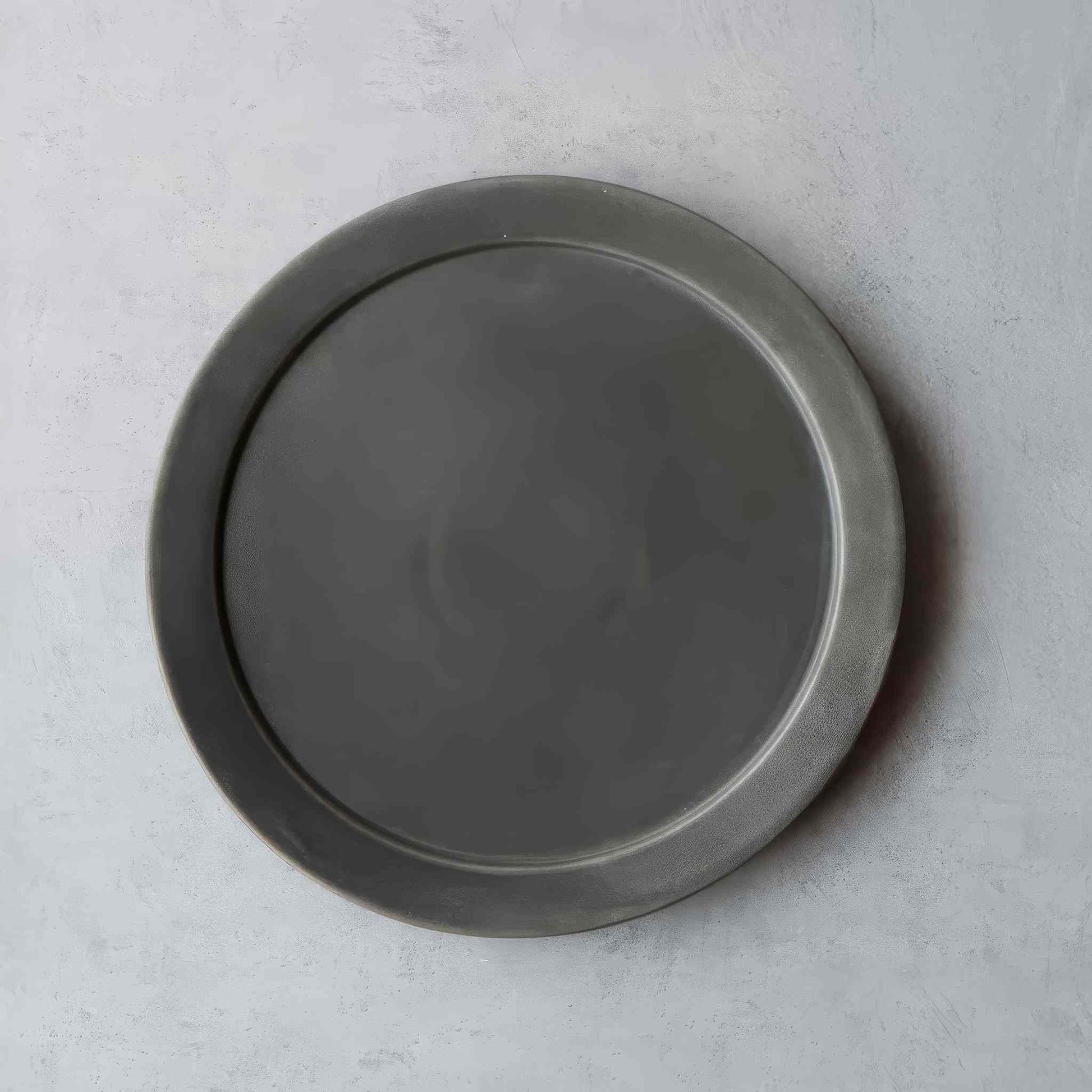 A black and white, handcrafted plate with a unique, natural finish, evoking the tradition of Arita ware, Japan's celebrated porcelain heritage.