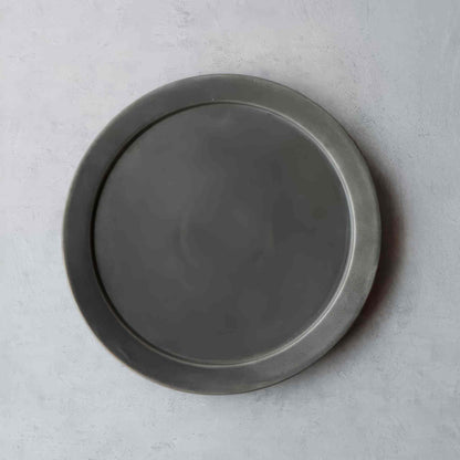 A black and white, handcrafted plate with a unique, natural finish, evoking the tradition of Arita ware, Japan's celebrated porcelain heritage.