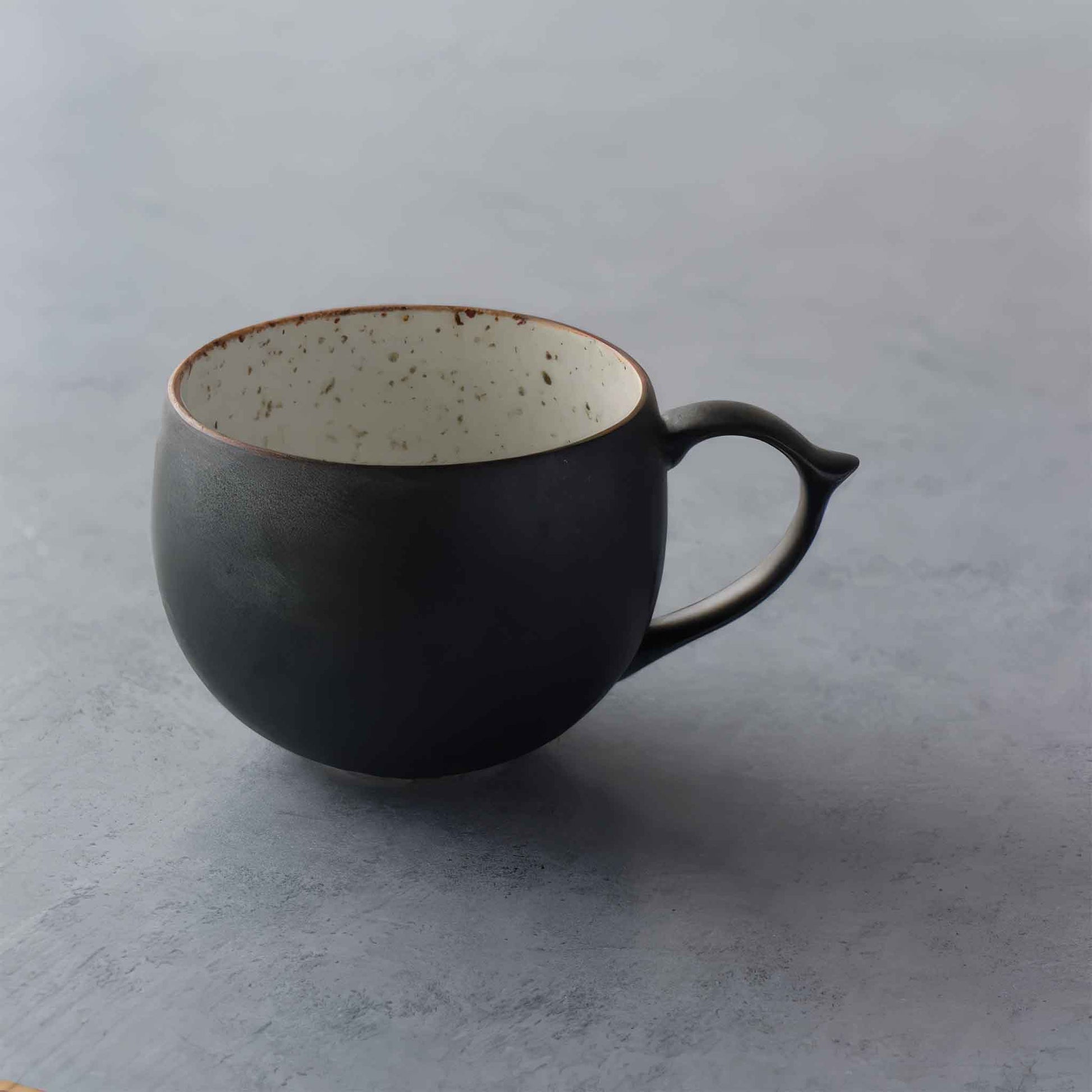Handcrafted black and white wabi-sabi ceramic mug, Arita ware on a neutral background.