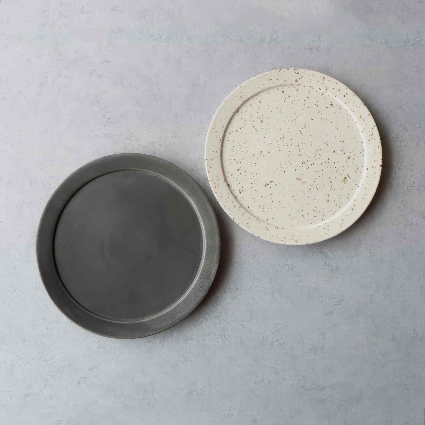 Handmade Arita-style plate in black and white, with a speckled glaze, on a neutral background.