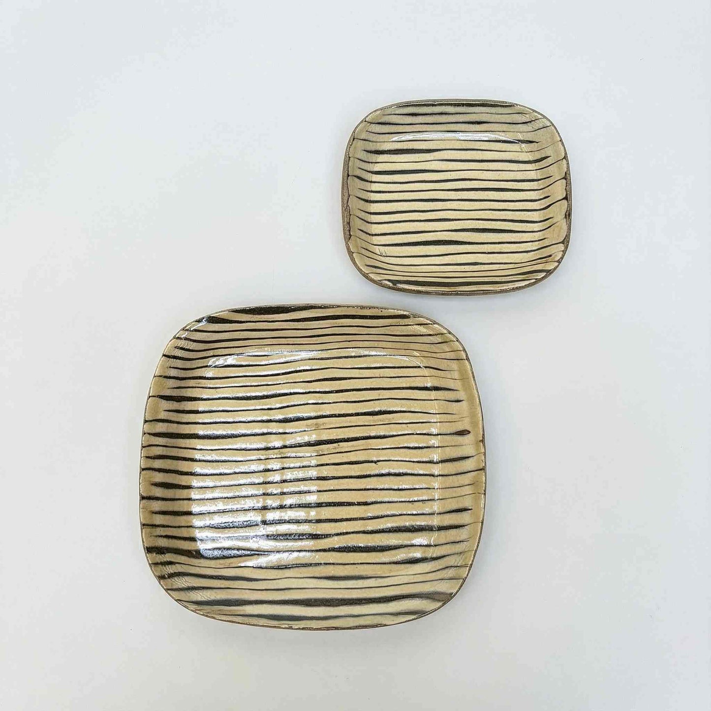 Handmade slipware square plate with hand-applied surface patterns in a neutral color, set against a white background.