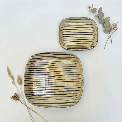 Handmade square plate with hand-applied surface patterns in a neutral color, set against a white background.