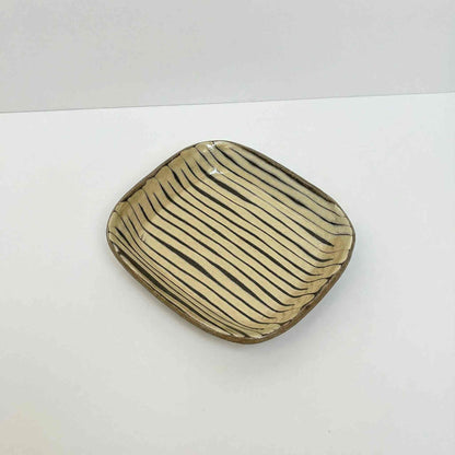 Handmade square plate with unique, hand-applied surface patterns in a neutral color.