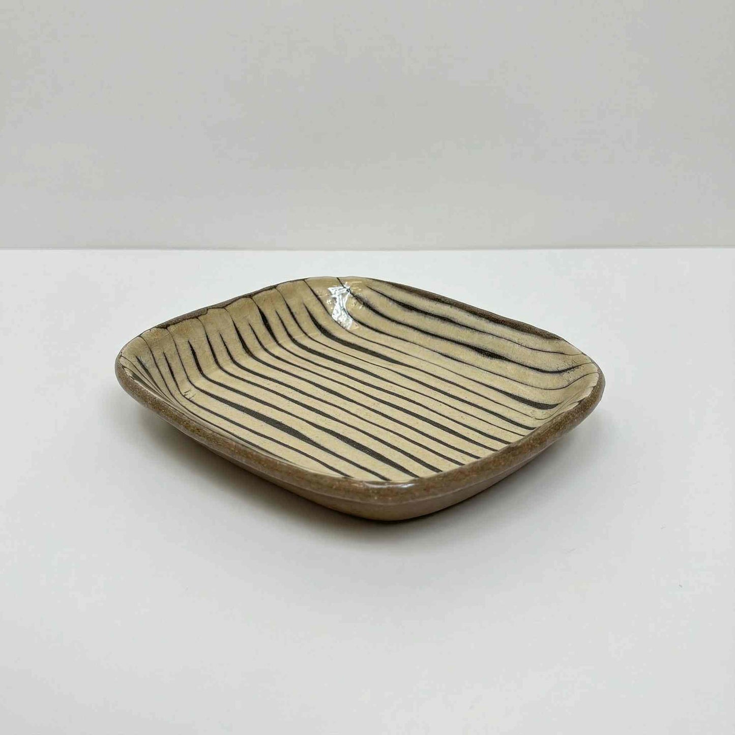 Handmade square plate with unique, hand-applied surface patterns in earthy tones, created by Japanese ceramicist Momoko Shiohata.