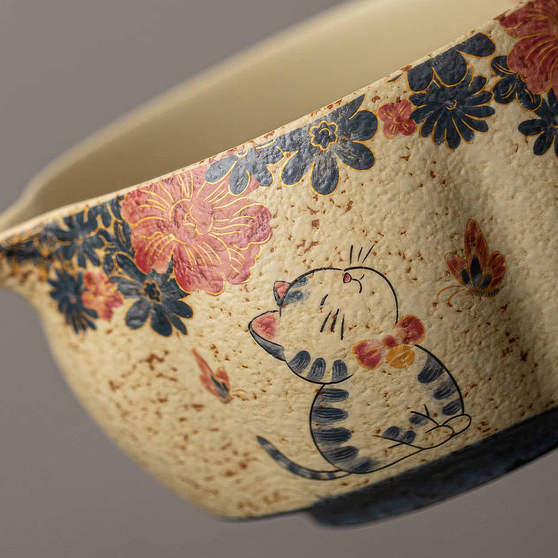 A hand-painted, blue and white flint red matcha bowl set with a cat design, set against a neutral background.