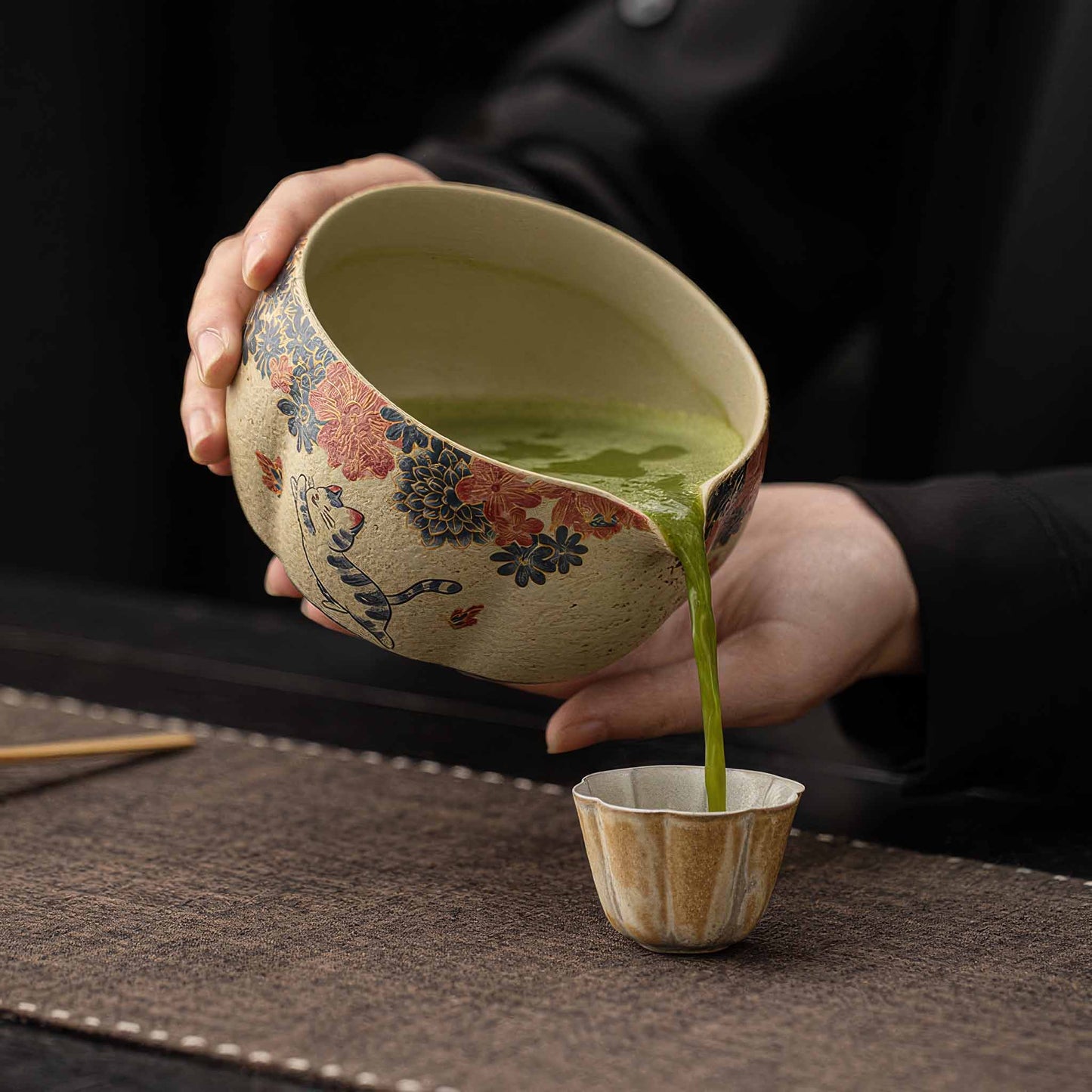 Hand-painted blue and white flint red matcha bowl set with tea scoop and whisk on a dark table.