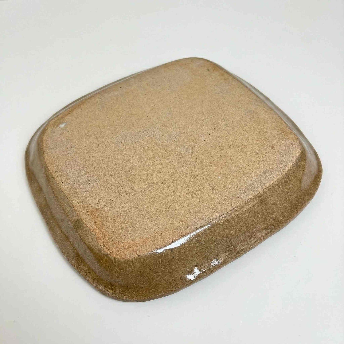 A handcrafted, square-shaped plate with a natural, earthy tone, made from slipware by Japanese ceramicist Momoko Shiohata.