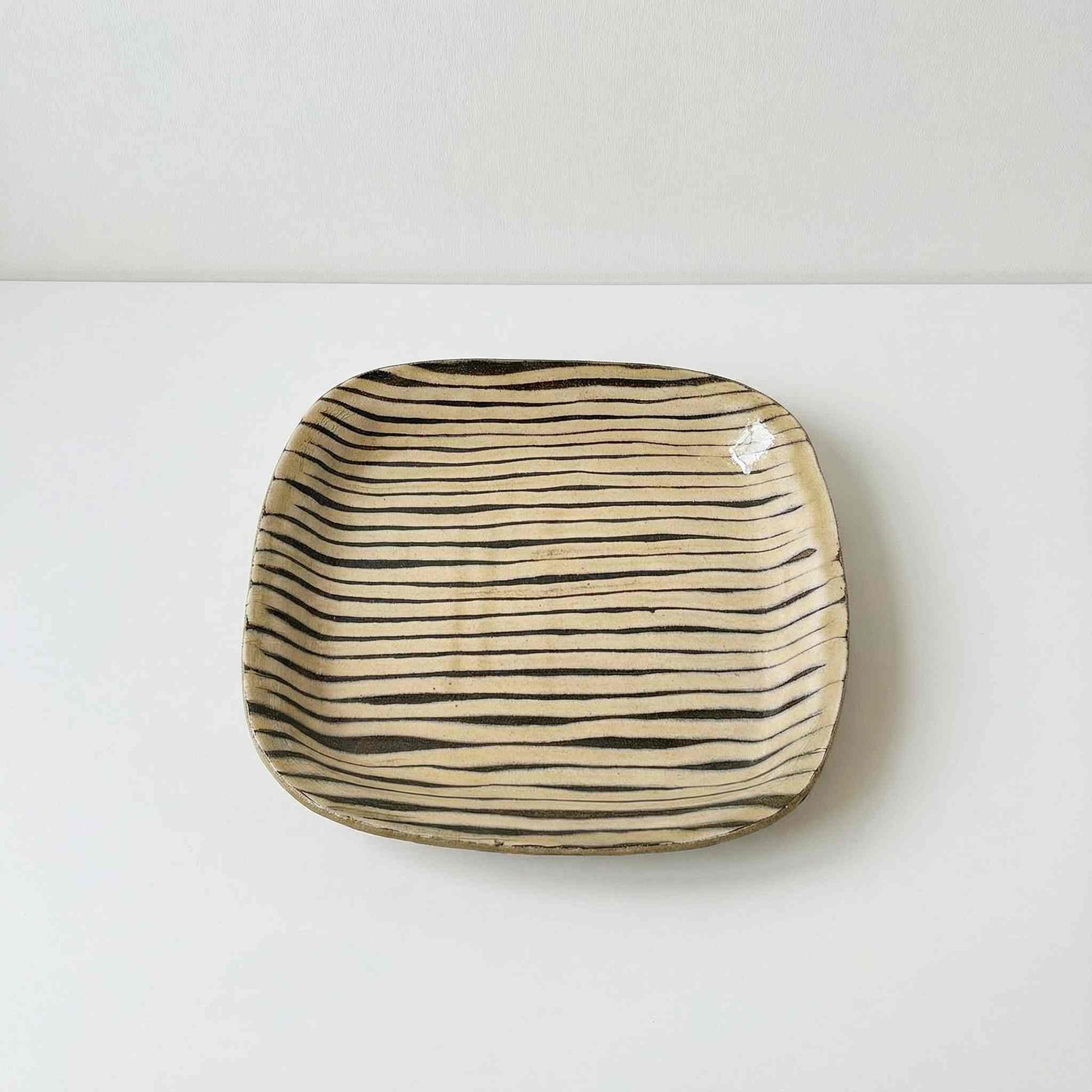 Handcrafted square plate with a unique, wavy design.