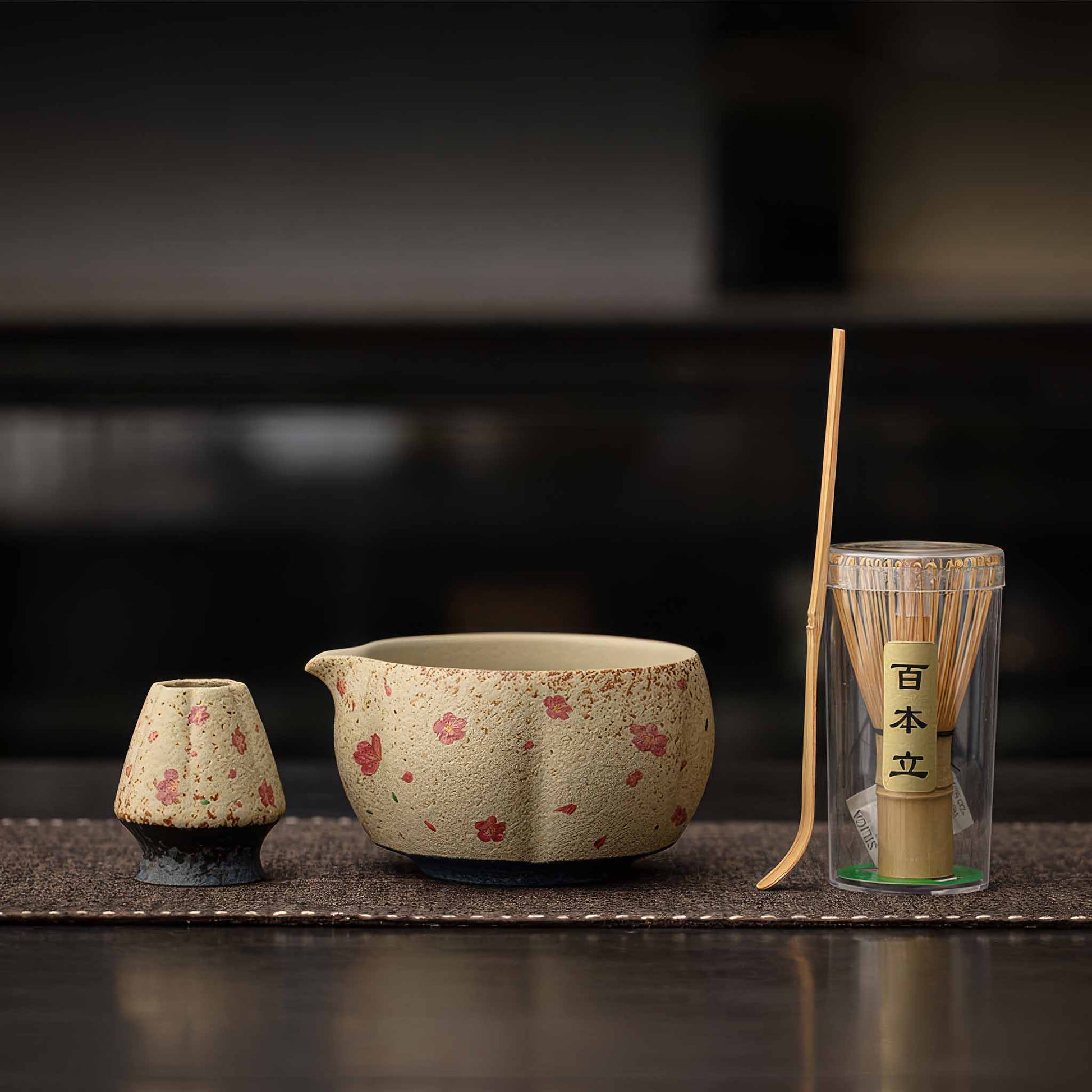 A hand-painted, hand-crafted matcha bowl set with a traditional Japanese design, including a matcha whisk and a small ceramic bowl.