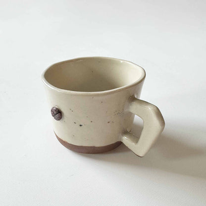 Handmade terracotta espresso cup with earthy brown base and handle, set against a neutral white background.