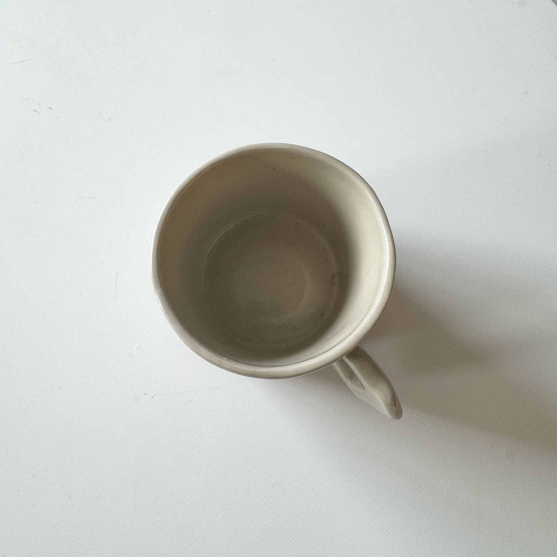 Handmade white ceramic espresso cup on a white surface.