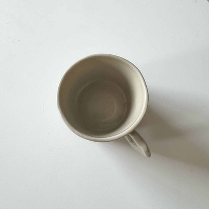 Handmade white ceramic espresso cup on a white surface.