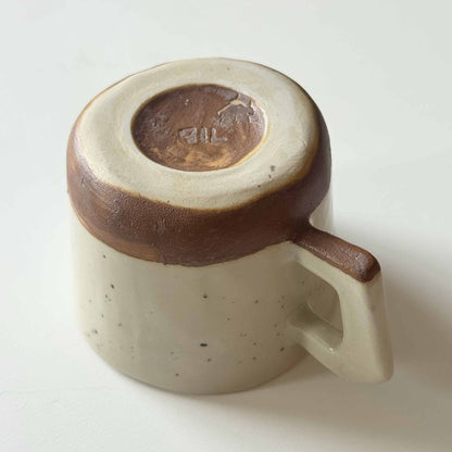 Handmade ceramic espresso cup with a brown and cream speckled glaze, set against a neutral white background.