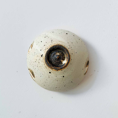 A small, off-white, handcrafted ceramic soup cup with a speckled glaze, set against a plain white background.