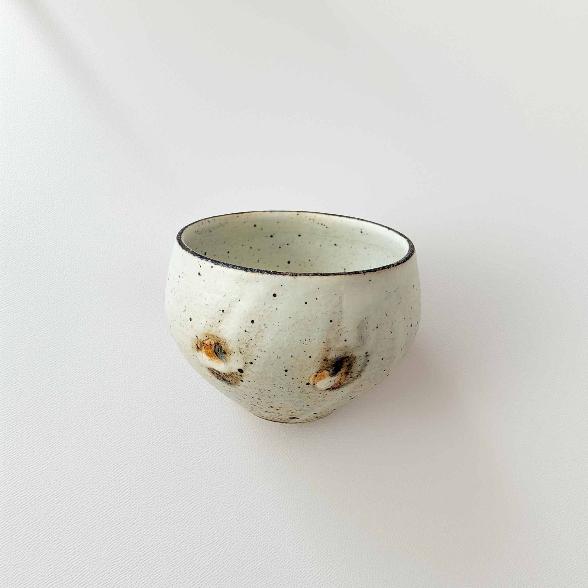 A small, handcrafted white ceramic soup cup with a natural glaze and subtle textures, set against a plain white background.