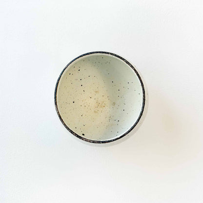 A small, handcrafted soup cup with a natural, earthy glaze, set against a neutral background.
