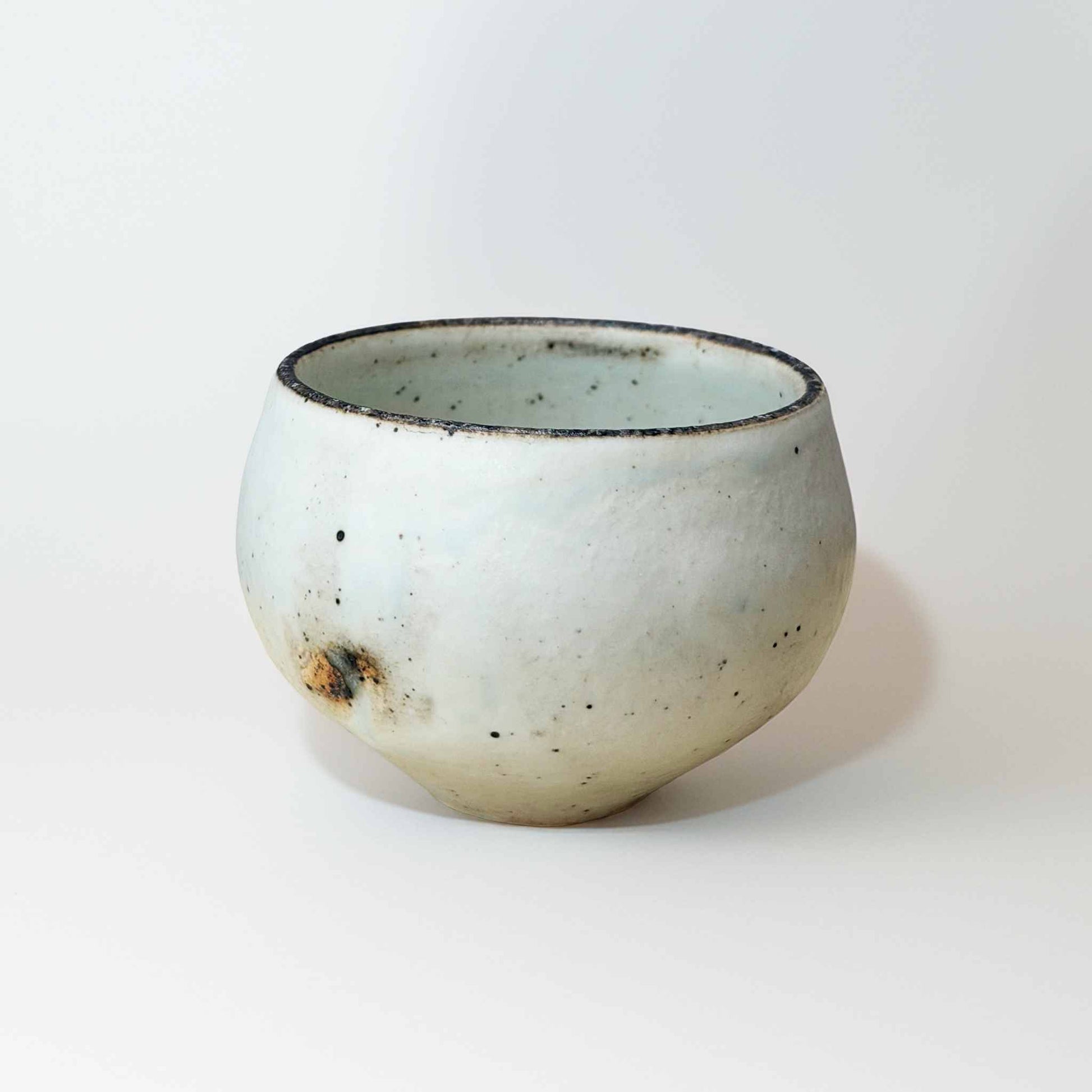 A small, handcrafted white ceramic soup cup with a natural glaze and subtle textures, set against a plain white background.