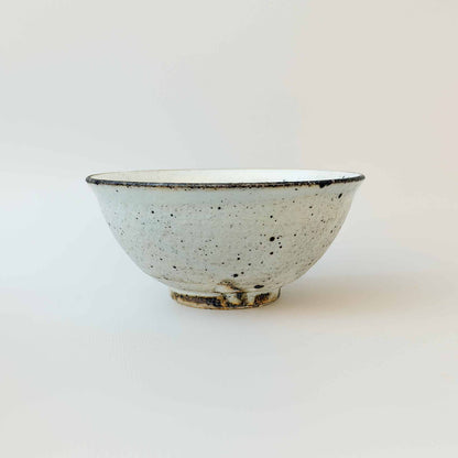 A small, white, handcrafted V-shaped bowl with a kohiki glaze, set against a plain white background.