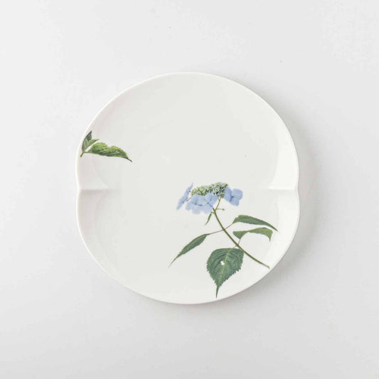 A delicate, white, porcelain plate with a small, blue daisy design and green leaves.